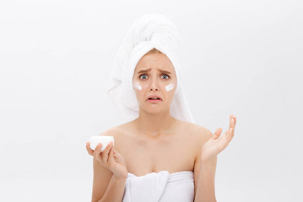 disappointed young woman with foam on the face and a cream in her hand. - Foto, imagen