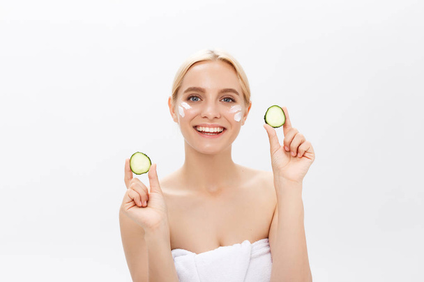 Portrait of the playful girl covering an eye by a slice of a cucumber, isolated on white. - Photo, image
