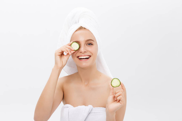 Young beautiful nude girl smiling hiding eyes behind cucumber slices over white background. Beauty skincare and cosmetology - Foto, Bild