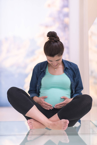 happy pregnant woman enjoying pregnancy relaxing at home sitting on the floor - Foto, Imagen