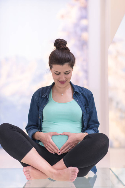 happy pregnant woman enjoying pregnancy relaxing at home sitting on the floor - Fotoğraf, Görsel