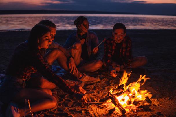 jóvenes amigos tienen picnic con hoguera en la playa
 - Foto, Imagen