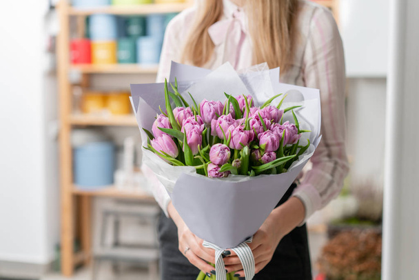 Sunny spring morning. Young happy woman holding a beautiful bunch of lilac tulips in her hands. Present for a smiles girl. - Photo, Image