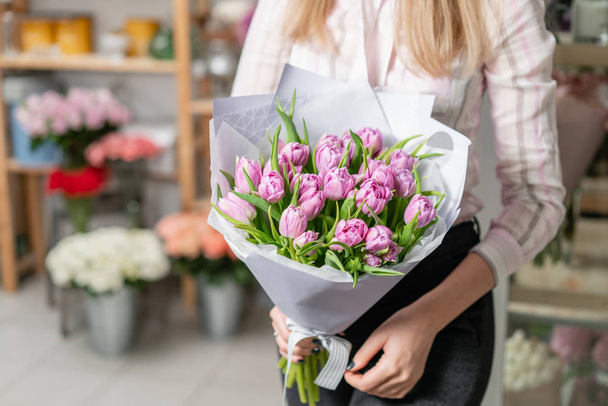 Napsütéses tavaszi reggelen. Fiatal, boldog nő egy szép lila tulipán csokor tartja a kezében. Jelenleg egy mosoly lány. - Fotó, kép