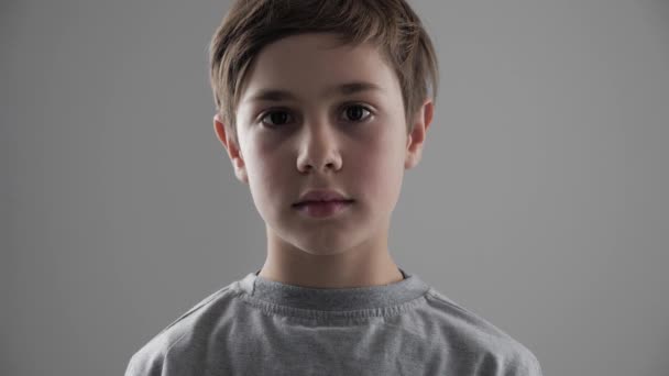 Portrét roztomilý mladých 11-12 let starý brachu při pohledu na fotoaparát na bílém pozadí - Záběry, video