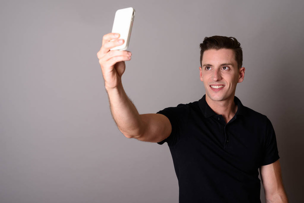 Young handsome man using mobile phone to take selfie - Фото, изображение