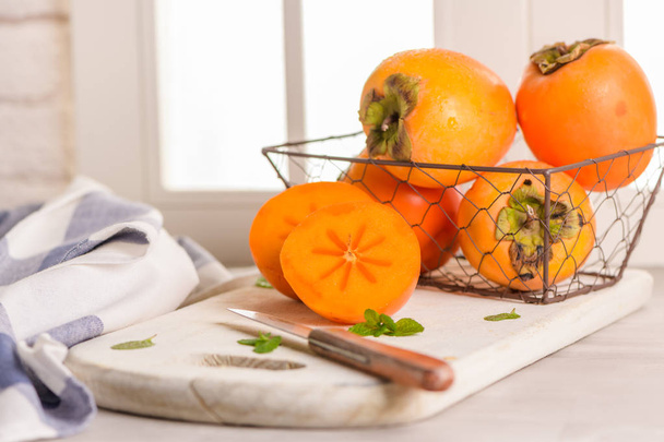 Delicious fresh persimmon fruit on kitchen countertop. - Foto, imagen