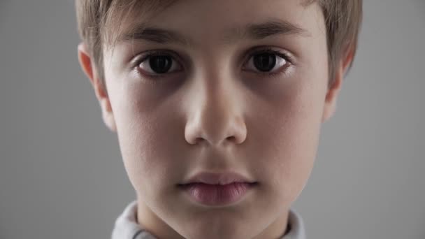 Portret cute młodych 11-12 roku chłopiec ogląda aparat na białym tle z bliska - Materiał filmowy, wideo