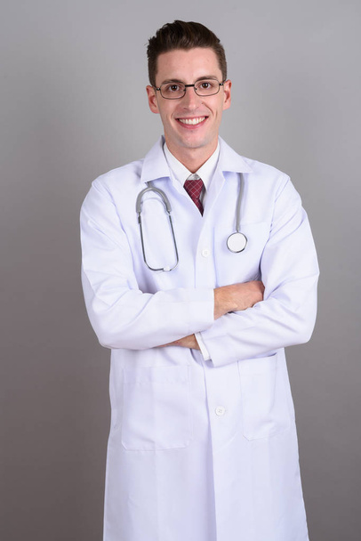 Fiatal jóképű férfi orvos mosolyogva karokkal keresztbe - Fotó, kép