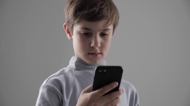 Portré, fiatal 11-12 év régi fiú használ Smartphone, fehér háttér - Felvétel, videó