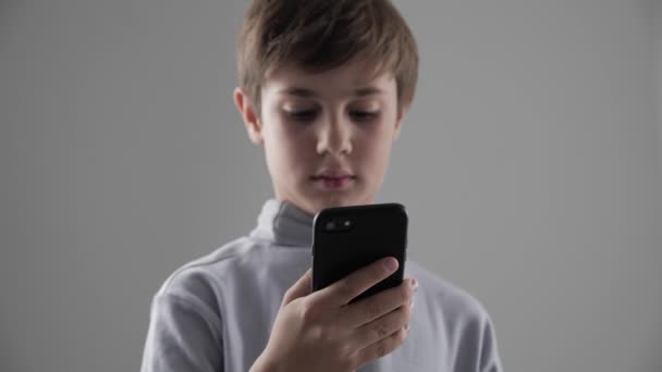 Portré, fiatal 11-12 év régi fiú használ Smartphone, fehér háttér - Felvétel, videó