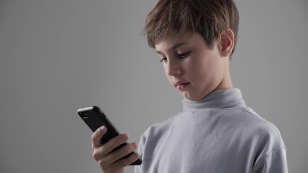 Retrato de niño de 11 - 12 años usando Smartphone sobre fondo blanco
 - Metraje, vídeo
