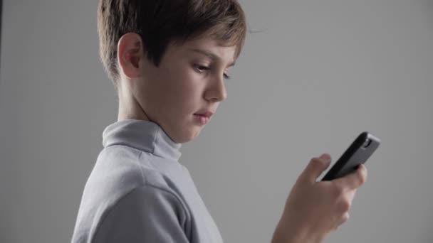 Portrait de jeune garçon de 11 à 12 ans utilisant un smartphone sur fond blanc
 - Séquence, vidéo