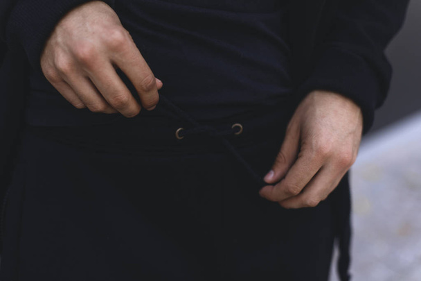 Homme attachant la dentelle sur un pantalon de sport. Homme en costume de sport noir. Détails des vêtements
.  - Photo, image