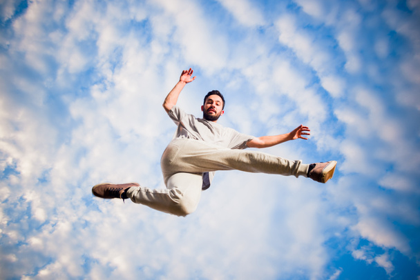 Młody człowiek ćwiczy parkour pod błękitnym niebem - Zdjęcie, obraz