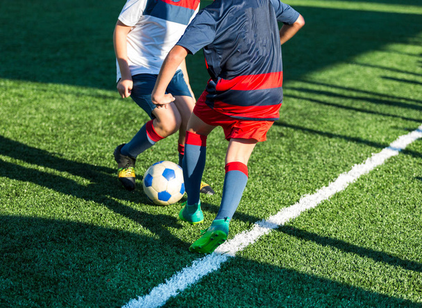 サッカー チーム - 赤、青、白のスポーツ ウエアで男の子グリーン フィールド上にサッカーします。ドリブルの男の子。ドリブルのスキル。ゲーム、トレーニング、アクティブなライフ スタイル、趣味、子供の概念のためのスポーツをチームします。 - 写真・画像