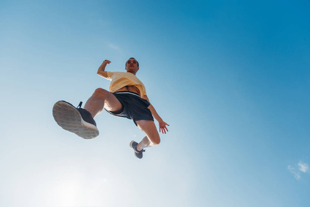 Youung man in de lucht terwijl opleiding parkour - Foto, afbeelding