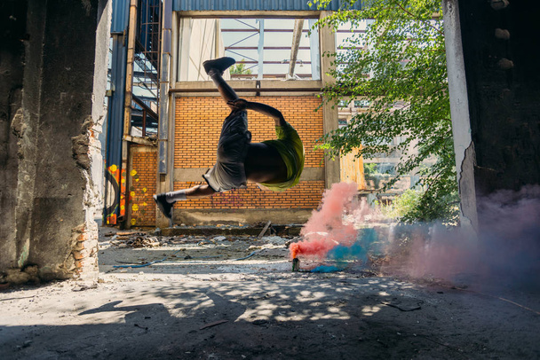 Parkour man training around colored smoke bombs - Фото, изображение