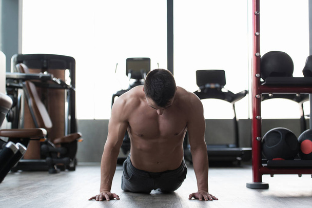 L'homme musculaire s'étire au sol dans une salle de gym et des muscles flexibles - modèle de remise en forme de bodybuilder athlétique musculaire
 - Photo, image
