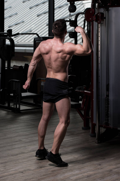 Handsome Young Man Standing Strong In The Gym And Flexing Muscles - Muscular Athletic Bodybuilder Fitness Model Posing After Exercises - Fotografie, Obrázek