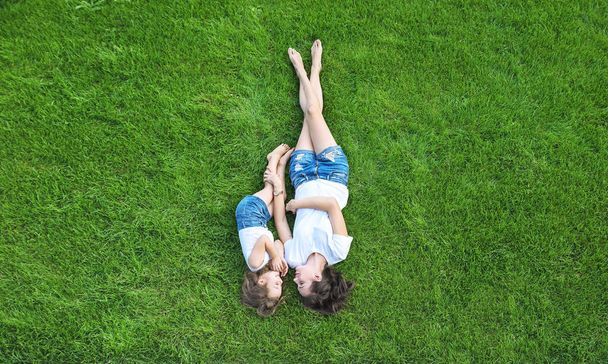 Conceptual portrait of a pretty mother relaxing with daughter on a fresh, green lawn - Fotografie, Obrázek
