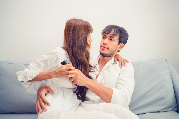 Casal jovem luta por controle remoto de TV no sofá na sala de estar em casa pela manhã
. - Foto, Imagem