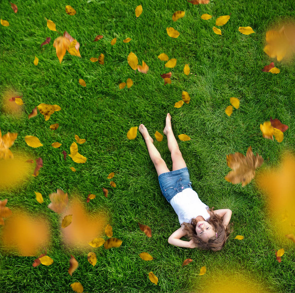 Niña relajada acostada en un prado verde y fresco
 - Foto, Imagen