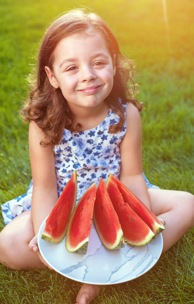 Retrato de sonrisa, linda chica sosteniendo rodajas de sandía en el jardín
 - Foto, imagen