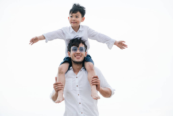 Onnellinen isä kantaa poikaansa kaulassa trooppisella hiekkarannalla kesällä
. - Valokuva, kuva