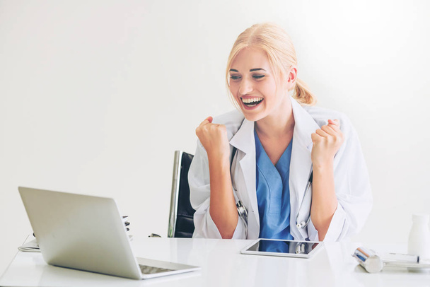 Happy successful woman doctor feels delightful in hospital or healthcare institute while working on medical report at office table. Success concept. - Фото, изображение