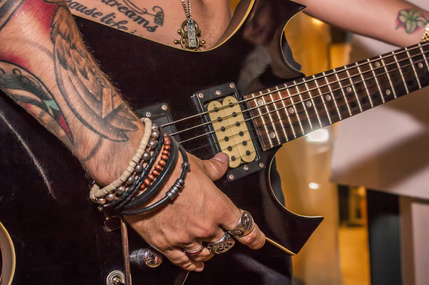 Detail of a tattooed boy playing electric guitar during a rock cone. - Φωτογραφία, εικόνα