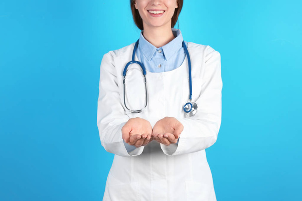 Female doctor showing open hands on color background, closeup - Фото, изображение