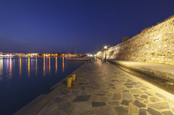 The wall of the old castle fortress in the city of Kos, Greece, night city landscape, view of the port with yachts and boats - Photo, image