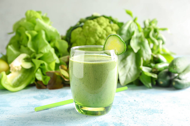 Bicchiere di frullato verde saporito e ingredienti su tavolo a colori
 - Foto, immagini