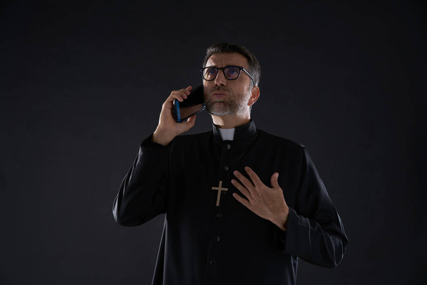 Priest talking smartphone phone funny expression - 写真・画像
