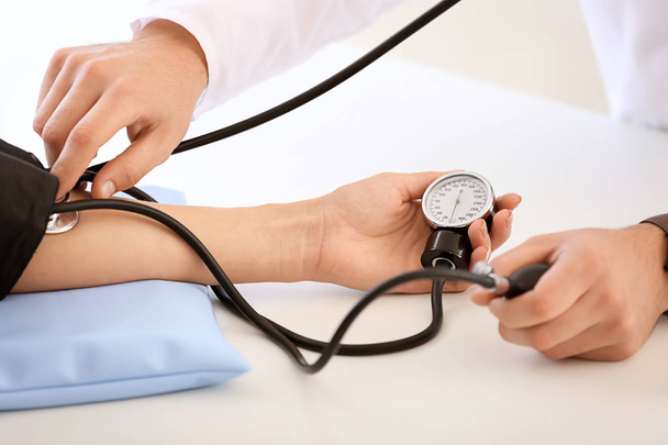 Male doctor measuring blood pressure of female patient in hospital - Foto, afbeelding