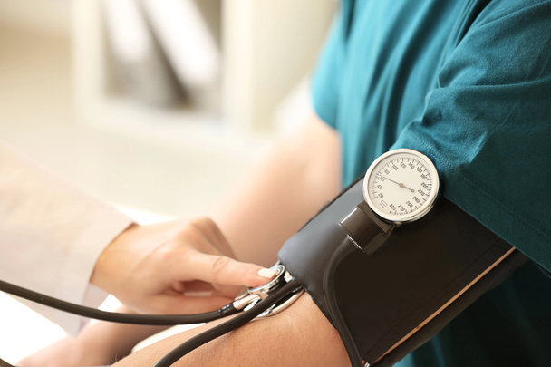 Жінка-лікар вимірює кров'яний тиск пацієнта чоловічої статі в лікарні
 - Фото, зображення