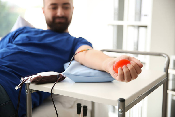 Man with grip ball donating blood in hospital - Zdjęcie, obraz