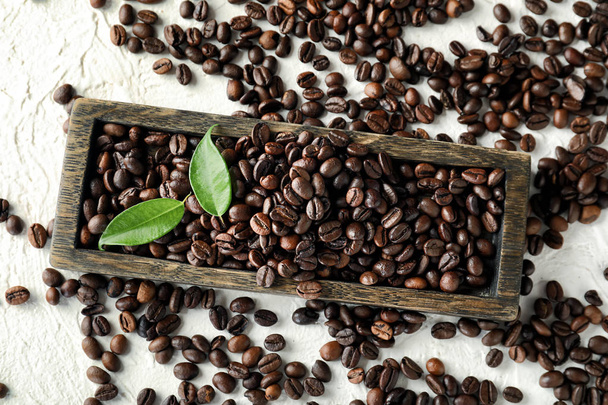 Board with roasted coffee beans on white table - Foto, Bild
