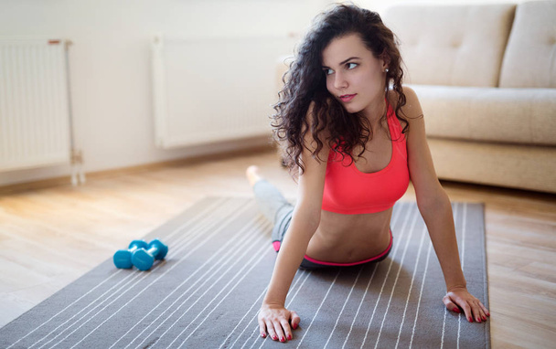 Young attractive sportswoman doing fitness exercises at home - Fotoğraf, Görsel