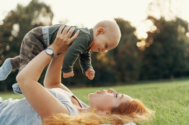 glückliche Mutter im Gras liegend beim Spielen mit ihrem Baby - Foto, Bild