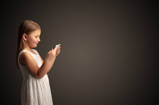 Cute little girl using tablet with dark background - Φωτογραφία, εικόνα