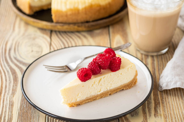 Piece of classic cheesecake with raspberries and coffee on a wooden background. Copy space. - Photo, image