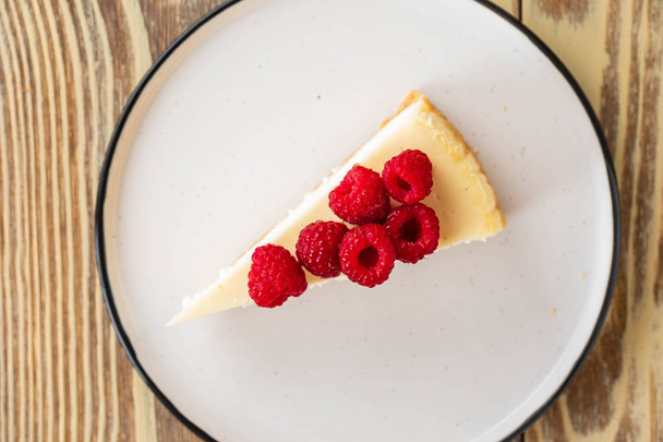 Piece of classic cheesecake with raspberries and coffee on a wooden background. Copy space. Top view. - Photo, Image