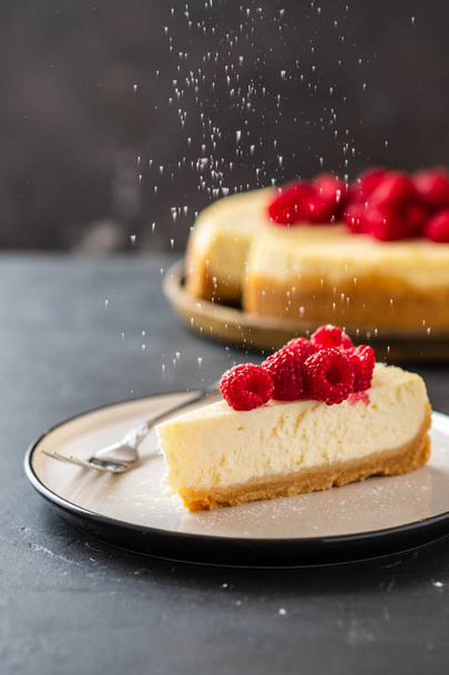 Slice of New York Cheesecake with raspberries on a dark background. - Foto, Bild