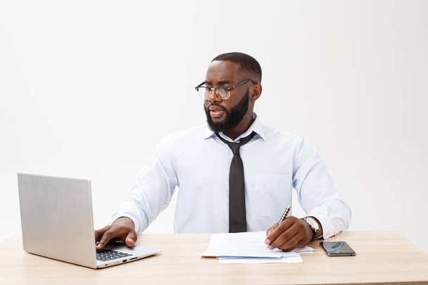 Business and success. Handsome successful African American man wearing formal suit, using laptop computer for distant work, looking at the screen with serious face expression. - 写真・画像