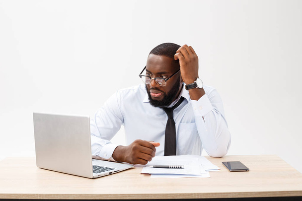 Biznes i sukcesu. Przystojny udanych African American człowiek ubrany oficjalne garnitur, przy użyciu komputera przenośnego do odległej pracy, patrząc na ekran z wyrazem twarzy poważne. - Zdjęcie, obraz