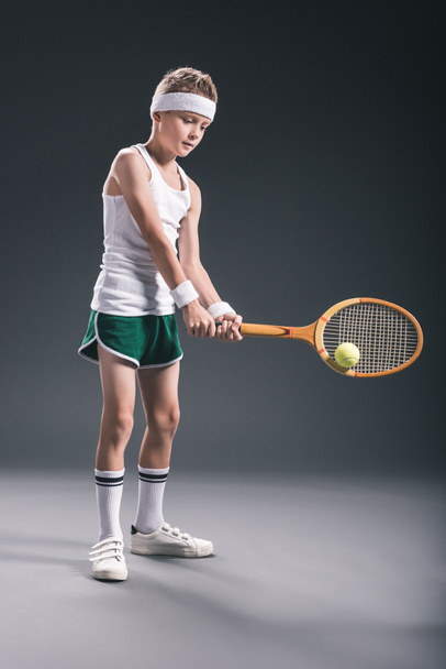 preteen boy in sportswear with tennis racket and ball on dark background - Foto, afbeelding