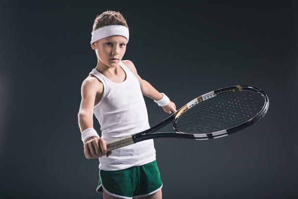 portrait of boy in sportswear with tennis racket on dark background - Photo, Image