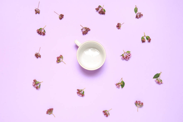 Floral wallpaper of flowers of oregano and cup on lilac background. - Valokuva, kuva